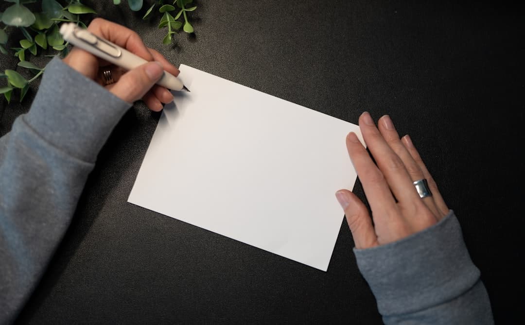 Hands writing a personal message on a blank card